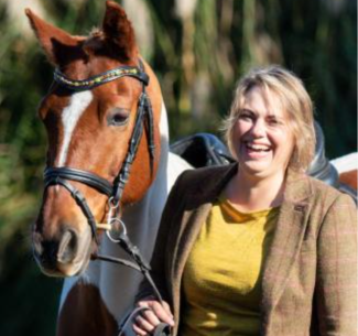 Dr. Trauger laughs, standing next to a horse